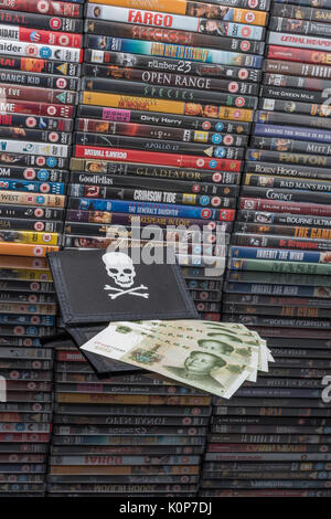 Gestapelte DVD-Filme & Schwarz pirate Portemonnaie und Chinesischen Renminbi Banknoten. Metapher der Chinesischen Urheberrecht IP-Diebstahl, US-China trade Krieg, China Piraterie. Stockfoto