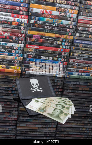 Gestapelte DVD-Filme & Schwarz pirate Portemonnaie und Chinesischen Renminbi Banknoten. Metapher der Chinesischen Urheberrecht IP-Diebstahl, US-China trade Krieg, China Piraterie. Stockfoto