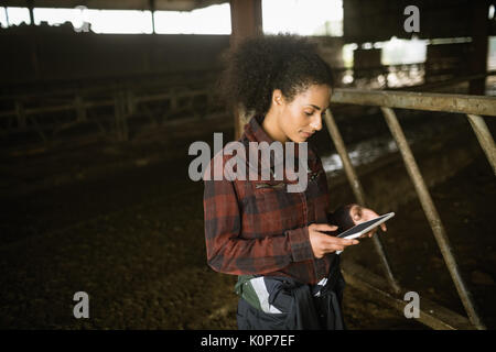 Schöne weibliche Landwirt mit digitalen Tablet in der Scheune Stockfoto