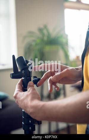 7/8 Hand des Fotografen anpassen der Ausrüstung während im Studio arbeiten Stockfoto