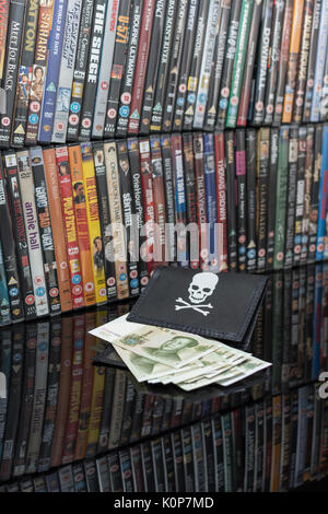 Gestapelte DVD-Filme & Schwarz pirate Portemonnaie und Chinesischen Renminbi Banknoten. Metapher der Chinesischen Urheberrecht IP-Diebstahl, US-China trade Krieg, China Piraterie. Stockfoto