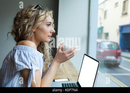 Seitenansicht der nachdenkliche Frau, Getränk am Tisch durch Fenster in Cafe Stockfoto