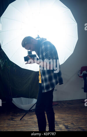Seitenansicht des Fotografen Fotografieren, während von Strobe Licht im Studio Stockfoto