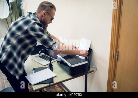 Seitenansicht der Fotograf das Papier in Drucker während der Arbeit im Studio Stockfoto