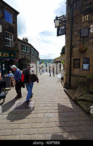 Menschen zu Fuß rund um den gepflasterten Hauptstraße im historischen Dorf Haworth, West Yorkshire, England, UK. Stockfoto