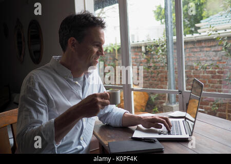 Man trinkt Kaffee am Computer in home office Stockfoto