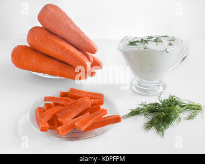 Carrot Sticks, ganze frische Karotten und saurer Sahne Sauce mit Kräutern Gesunde Ernährung Gesunde Ernährung auf weißem Hintergrund in Glasplatten und in einem Glas s Stockfoto