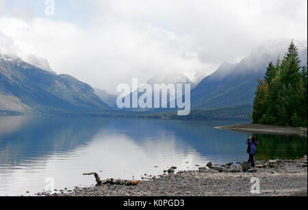 Frau fotografieren Blick auf See und Berge am Ufer von Lake Mcdonald - Glacier National Park, Montana Stockfoto