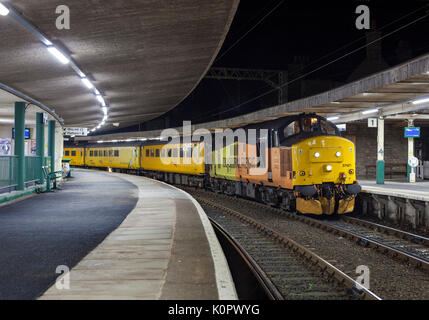 Colas Railfreight Lok der Baureihe 37 am Bahnhof Carnforth mit einem Network Rail-Infrastrukturüberwachungszug Stockfoto