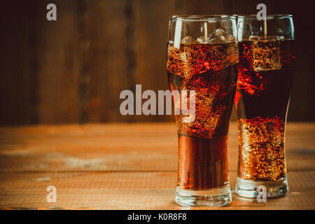 Schöne kalte fizzy cola Soda mit Würfeln Eis in Gläser Becher auf alten Holz- Hintergrund mit freier Speicherplatz Stockfoto