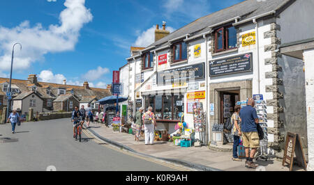 Allgemeine Ansicht von Menschen in den Geschäften entlang der Start der Fore Street suchen in dem kleinen Touristenort Tintagel an einem Sommertag. Cornwall, England, Großbritannien. Stockfoto