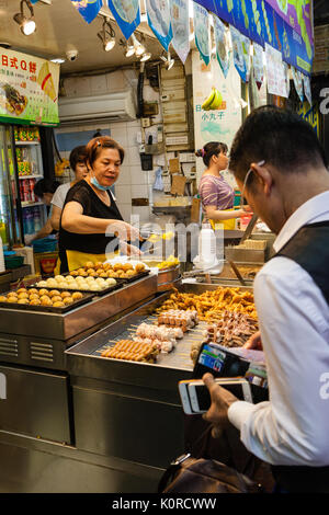 Hongkong - 11. Juli 2017: einem Straßenhändler verkaufen beliebte Snacks bei Fa Yuen Street Night Market in Kowloon. Dazu gehören stinky Tofu, Schweinedarm Stockfoto