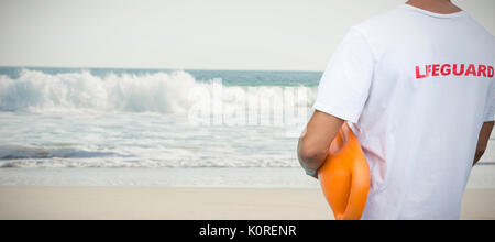 Den mittleren Abschnitt der männlichen Rettungsschwimmer mit Rescue Buoy gegen zwei Seesterne gehalten auf Sand Stockfoto