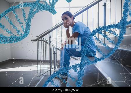 Digital composite Verunsicherter Arzt Frau sitzt mit 3D-DNA-Stränge Stockfoto