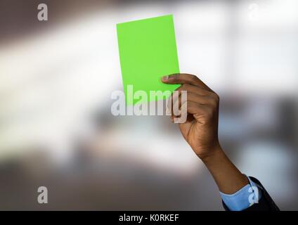 Digital composite einer Hand, die eine grüne Karte in helles Zimmer Stockfoto