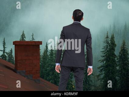 Digital composite der Geschäftsmann auf Dach mit Kamin und nebligen Wald Stockfoto