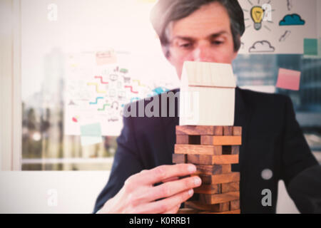 Unternehmer, die die Holzklötze am Tisch gegen adhäsiven Hinweise zum Fenster Stockfoto