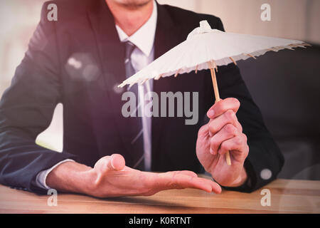 Das zusammengesetzte Bild im Geschäftsmann holding Papier Regenschirm Stockfoto