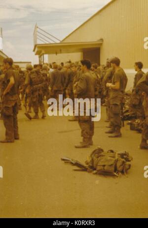 Eine große Gruppe von Soldaten in ihren Uniformen gesammelt wurden, zeigen alle in dieselbe Richtung, deren Bekämpfung Gangs gegen ein Gebäude, Vietnam, 1964 an die Seite gestellt wurde. Stockfoto