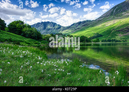 Idyllische Landschaft des Lake District, England im Frühjahr. Grünes Gras wächst an Mountain Lake Shore, Bäumen und grünen Hügeln im Wasser widerspiegelt, blaue Himmel. Stockfoto