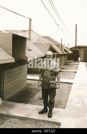 United States Army Sergeant stehen außerhalb der Kaserne während des Vietnam Krieges, tragen Uniform, Gläser, und rauchen eine Zigarette, 1964. Stockfoto
