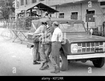 Amerikanische Soldaten stehen an einer militärischen Check Point während des Vietnam Krieges, stützte sich auf einen Ford Truck, Soldaten, die mit Sandsäcken und Stacheldraht, einem Maschinengewehr post im Hintergrund, 1966 sichtbar. Stockfoto