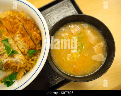 Traditionelle Suppe Udon, in einer schwarzen Platte, am Tisch. Japanisch Suppe namens Udon mit frittierten Shrimps oder Tempura. Suppe mit udon Nudeln und Garnelen. original Suppe udon aus Japan Stockfoto