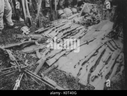 Erfasst Viet Cong Waffen, Gewehre und andere Waffen, ausgebreitet auf einer Decke, die Beine von einer Gruppe von Soldaten sichtbar herum stehen die erfassten Waffen, während des Vietnam Krieges, 1965. Stockfoto