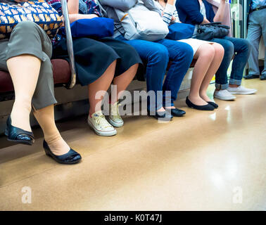 Tokio, Japan - Jan 2, 2016: in der Nähe der Beine pf Leute in einem Yamanote Bahn in Tokio, Japan. Das Eisenbahnwesen in Japan hat einen guten Ruf für Pünktlichkeit und Sicherheit Stockfoto