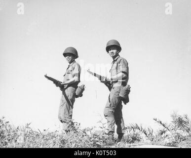 Ein Foto von zwei Soldaten der Armee der Republik Vietnam, die aufgeworfen werden auf einem Hügel, während ihre Bekämpfung Gewehre auf Taillenhöhe, Vietnam, 1968. Stockfoto