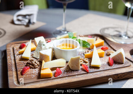 Verschiedene Käsesorten mit Nüssen und Beeren auf einem Holzbrett Stockfoto