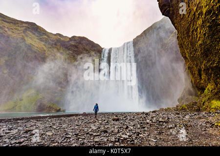 Junge weibliche stand vor der Skogafoss Wasserfall, Island Stockfoto