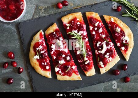 Urlaub Fladenbrot Vorspeise mit Preiselbeeren und Ziegenkäse, Overhead Szene auf einem Schiefer Hintergrund Stockfoto