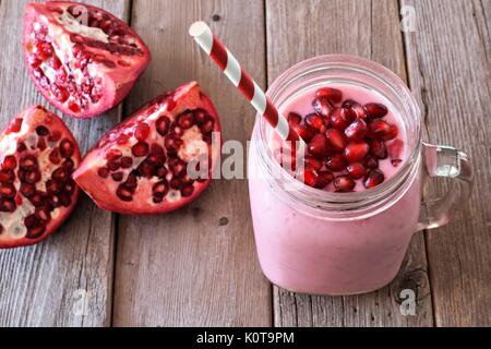 Granatapfel himbeer Smoothie in einem Glas Glas mit Granatapfel Stücke, Szene, rustikalen, mit Holz Stockfoto