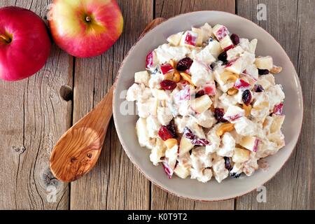 Herbst Salatteller mit Huhn, Äpfel, Nüsse und Preiselbeeren, oben auf rustikalen Holz Hintergrund Stockfoto