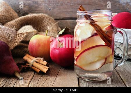 Herbst themed detox Wasser mit Apfel, Zimt und rote Birne in einem Marmeladenglas. Szene auf rustikalem Holz Hintergrund Stockfoto