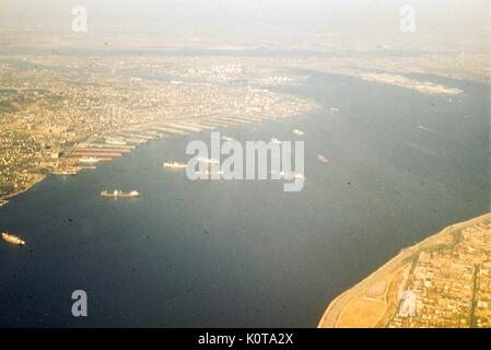 Antenne Blick Richtung Nordwesten Der verengt Gezeiten Meerenge zwischen der oberen und der unteren Schächte auf den Hafen von New York, New York City, 1957. Im Hintergrund über den oberen Rand des Rahmens der New Jersey Küste und den Hafen von Newark. Über Newark Bay ist Bayonne, New Jersey, wo das Militär Ocean Terminal auf der östlichen Seite befindet. Südlich der Constable Haken Bereich auf den Kill Van Kull Wasser-strasse, die dem Festland trennt sich von der North Shore von Staten Island. In der Mitte, von links nach rechts entlang der Küste links, sind den Nachbarschaften von Rosebank, Stapleton, Tompkinsville und St. Ge Stockfoto