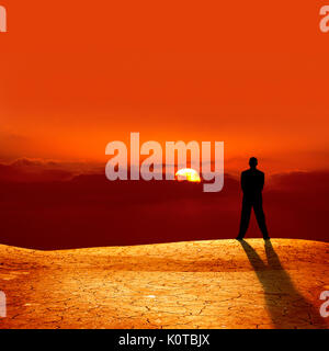 Konzeptionelle Bild der Silhouette Geschäftsmann auf Risse trockene Landschaft Sonnenuntergang beobachten Stockfoto