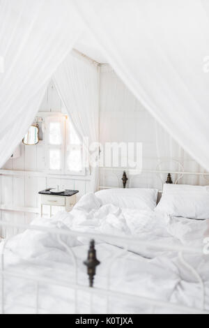 Weiß Bett am Morgen in Light vintage Zimmer aus Holz. Innen in der Farbe Weiß Stockfoto