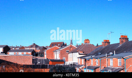 Englisch Haus und Kirche mit blauem Himmel. Traditionelle britische Dorf mit brick House an einem sonnigen Tag im Winter. Stockfoto