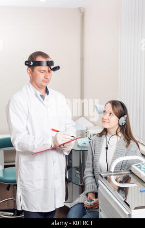 Arzt otolaryngologist des Patienten geprüft. Diagnose der Anhörung eine spezielle Apparatur mit Kopfhörern. Stockfoto