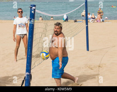 Übergewichtige Menschen spielen Volleyball am Strand in Spanien Stockfoto