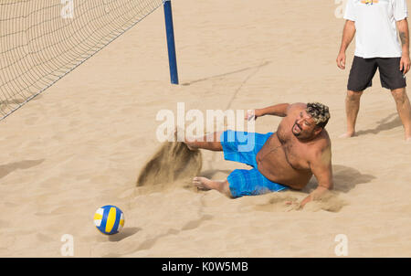 Übergewichtige Menschen spielen Volleyball am Strand in Spanien Stockfoto