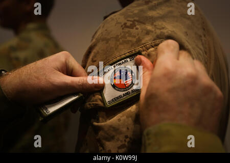CAIRNS, Australien - US Marine Cpl. Michael Smith, rifleman, Firma K, 3.BATAILLON, 4. Marine Regiment, Marine Drehkraft Darwin, erhält einen Patch von Brigadier Neil Sweeney, Kommandant der Übung Kowari 2017, während der Eröffnungsfeier für die Ausübung 23.08.2017. Während der Zeremonie alle teilnehmenden Mitglieder wurden Patches, um die Übung zu gedenken. Kowari ist eine jährliche Abenteuer Ausbildung Tätigkeit in Australien statt Trilaterale militärische Beziehungen, Vertrauen und Zusammenarbeit zwischen Australien, China und den Vereinigten Staaten zu stärken. (U.S. Marine Corps Foto von Sgt. Emmanu Stockfoto