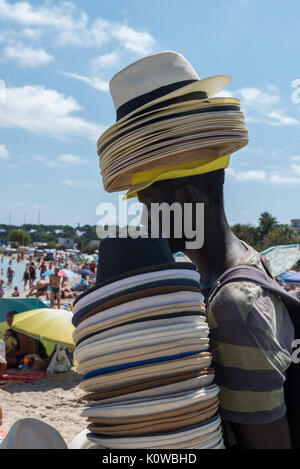 Ein afrikanischer Mann verkauft Strohhüte auf dem Strand in Antibes, Frankreich Stockfoto