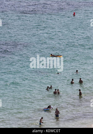 Touristen schwimmen oder genießen Sie maritimen Tätigkeiten, wie sie in den Strand von Magaluf in der spanischen Baleareninsel Mallorca sunbatthe Stockfoto