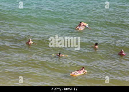 Touristen schwimmen oder genießen Sie maritimen Tätigkeiten, wie sie in den Strand von Magaluf in der spanischen Baleareninsel Mallorca sunbatthe Stockfoto