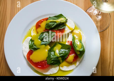 Caprese Salat mit Mozzarella, heirloom Tomaten, Basilikum, mit Honig Senf Dressing und Weißwein. Farben der italienischen Flagge: Rot, Grün, Weiß Stockfoto