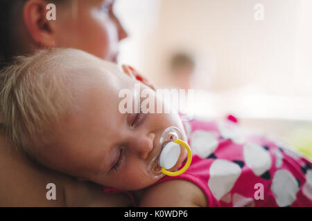 Junge Mutter hält ihr schlafendes Neugeborenes Stockfoto