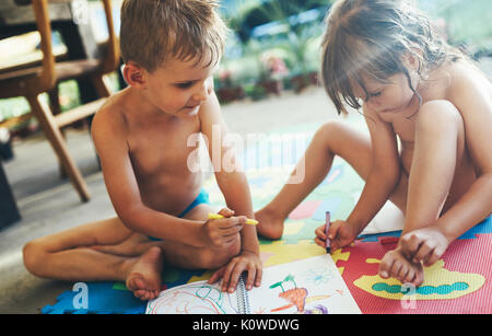 Kleine Jungen und Mädchen zeichnen mit Buntstiften Stockfoto